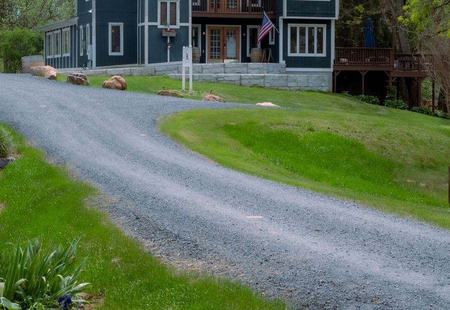 Gravel driveway curving across open ground toward a house